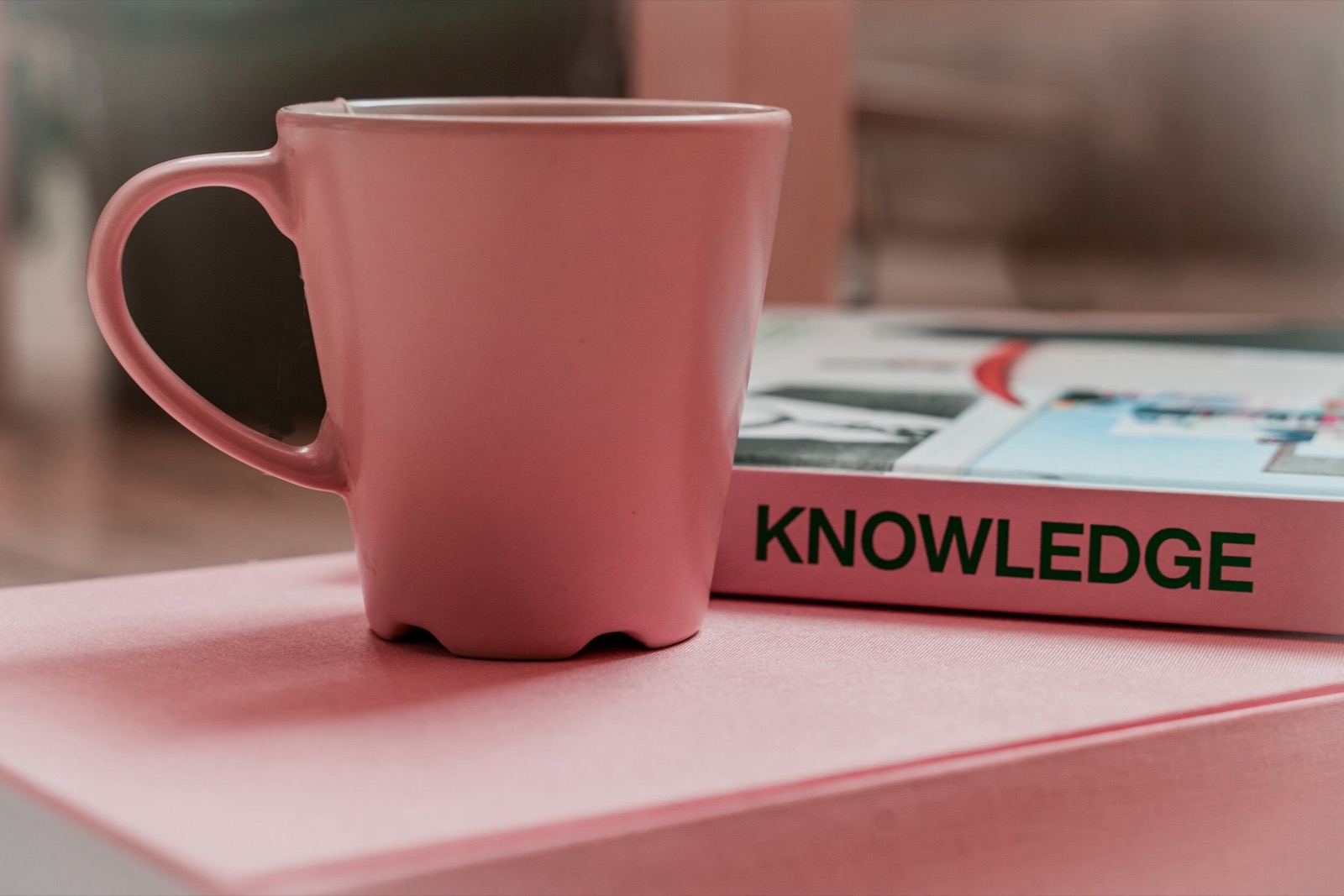 Kranus Health: Rosa Tasse neben Buch mit Titel “Knowledge”