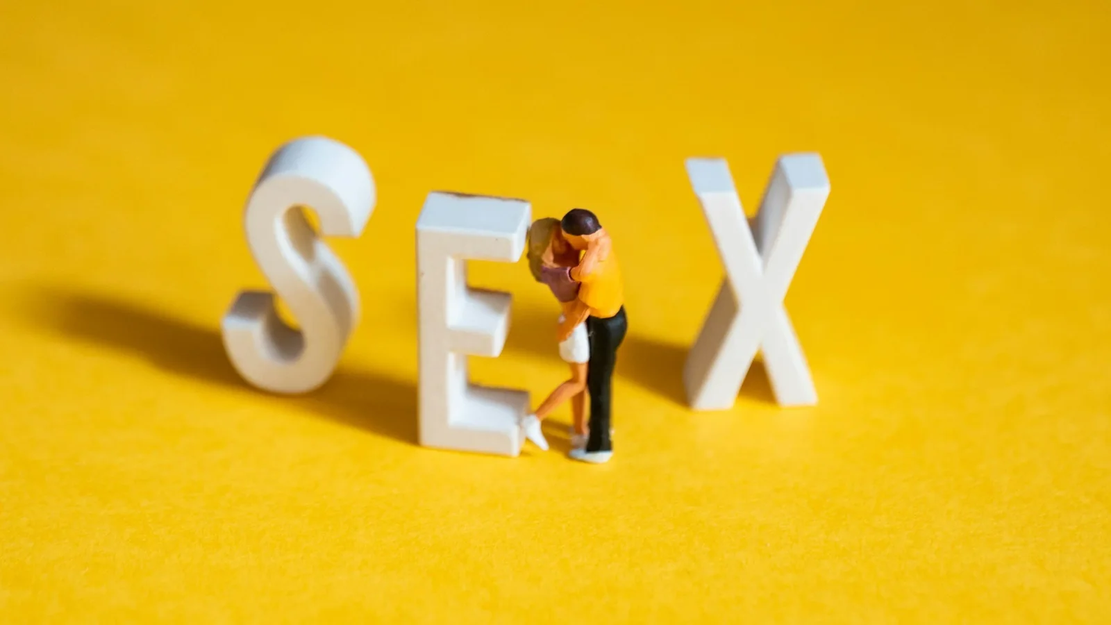 Kranus Health: Buchstaben die das Wort Sex formen vor gelbem Hintergrund